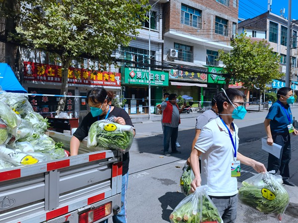 社区工作人员正在卸蔬菜包