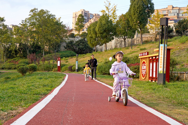 2023年11月17日，贵州省纳雍县白水河湿地公园，小朋友在刚刚铺装的彩色沥青健身步道上骑单车。 杨英摄