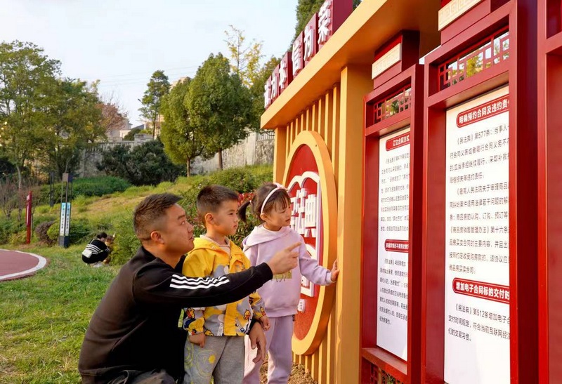 贵州省纳雍县一名市民正指着法治文化宣传标牌教小孩认“字”  杨英摄.jpg