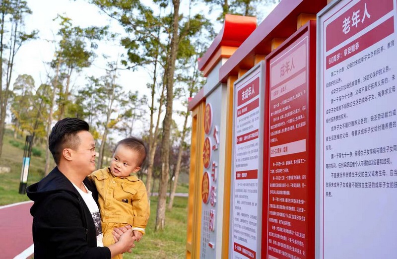 贵州省纳雍县一名市民正在看法治文化宣传标牌上的“法”文化 杨英摄.jpg