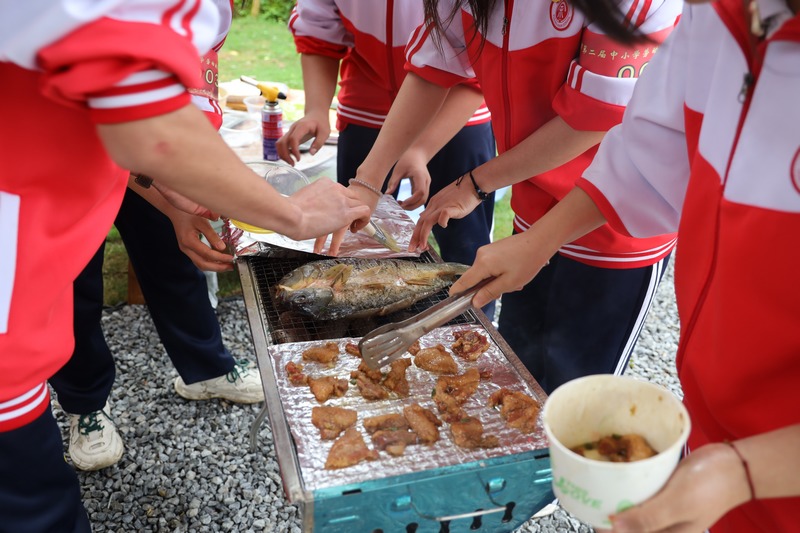 学生们相互配合烤鱼、烤肉。